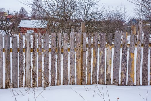 wooden fence of boards nailed to the crossbar on a winter day