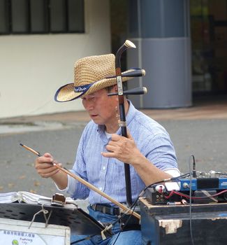 KAOHSIUNG, TAIWAN -- FEBRUARY 16, 2018: A street musician plays the erhu, a two-stringed Chinese fiddle, with a long bow.
