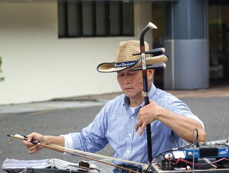 KAOHSIUNG, TAIWAN -- FEBRUARY 16, 2018: A street musician plays the erhu, a two-stringed Chinese fiddle, with a long bow.