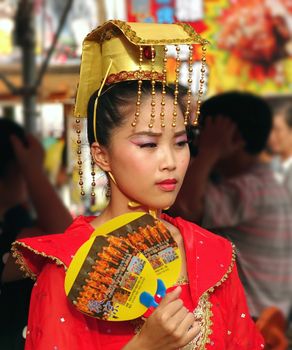 KAOHSIUNG, TAIWAN -- AUGUST 15, 2015: A beautiful female dancer with an elaborate headdress awaits her turn at the outdoor Third Prince temple carnival.
