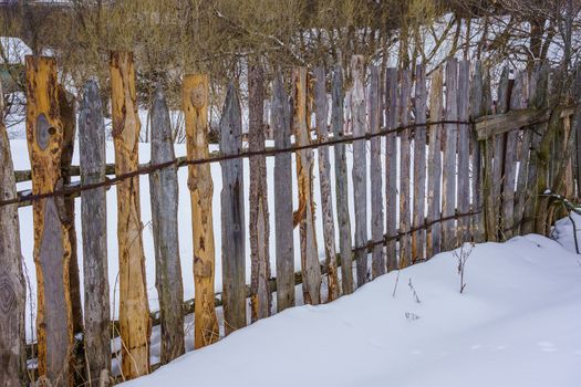 wooden fence of boards nailed to the crossbar on a winter day