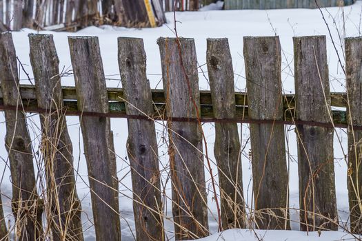 wooden fence of boards nailed to the crossbar on a winter day