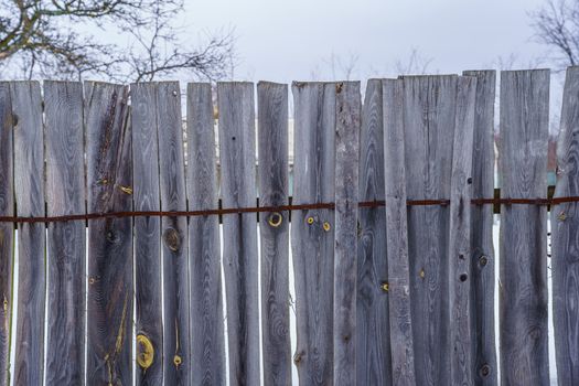 fence around the garden of planks fastened with nails and a metal strip