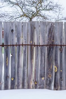 fence around the garden of planks fastened with nails and a metal strip