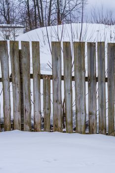 wooden fence of boards nailed to the crossbar on a winter day