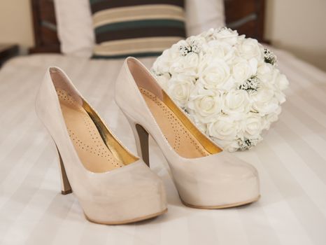 Closeup detail of bridal high heeled platform stiletto wedding shoes with flower bouquet