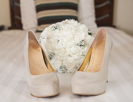 Closeup detail of bridal high heeled platform stiletto wedding shoes with flower bouquet