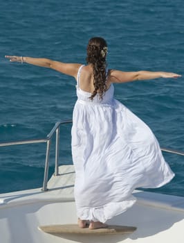Newlywed bride posing on the bow of a yacht at sea