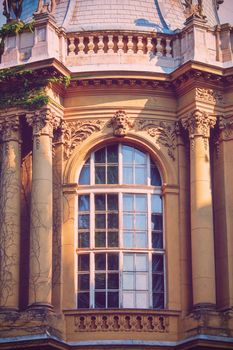 Arched window with a beautiful ancient stone relief ornamental decoration, portrait, floral elements and pillars. Vajdahunyad Castle in the City Park of Budapest, Hungary, Europe. Old decorative European facade detail.