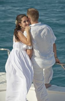 Newly married couple embracing while stood on the bow of a boat