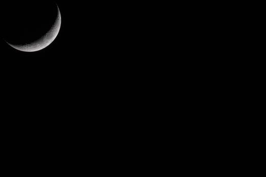 Crescent Moon against black sky at night with large copy space