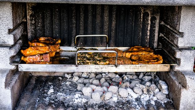 Preparation of a BBQ - wood burned down - charcoal at maximum heat - food ready to serve and kept on the side without coal