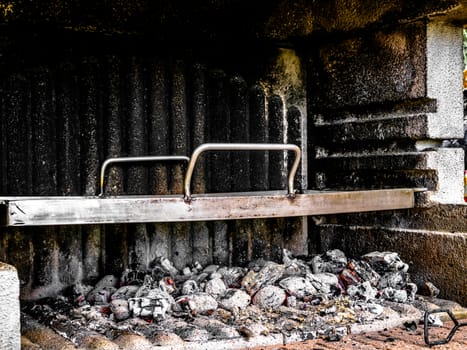 Firewood almost burnt down in a concrete grill - grill plate installed and ready to start the barbeque