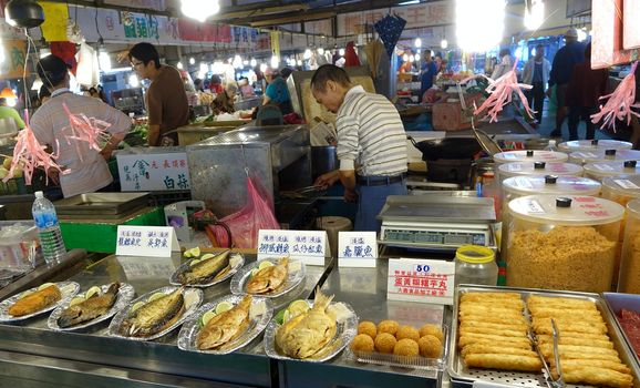 KAOHSIUNG, TAIWAN -- MARCH 20, 2014: A vendor sells fried fish, fish sausages and fish balls at a traditional Chinese outdoor market.