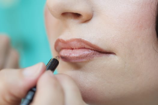 Closeup detail of woman having lipstick and lip liner applied in beauty salon