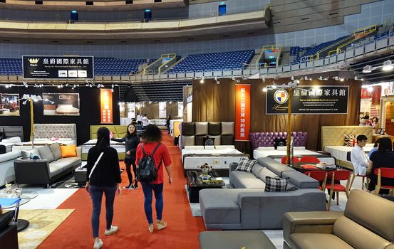 KAOHSIUNG, TAIWAN -- APRIL 5, 2019: People look at living room sets and beds at a furniture promotion event.
