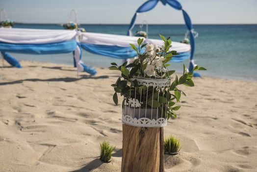 Setup of wedding day marriage aisle with drapes and arch on sandy tropical beach paradise to open ocean background 