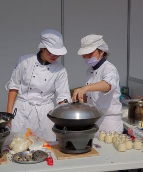 KAOHSIUNG, TAIWAN -- NOVEMBER 28, 2015: Two chefs prepare a steamer for the cooking competition during the 2015 Hakka Food Festival, which is a yearly public outdoor event.
