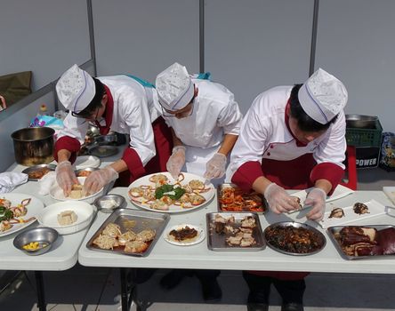 KAOHSIUNG, TAIWAN -- NOVEMBER 28, 2015: Three chefs prepare dishes for the cooking competition during the 2015 Hakka Food Festival, which is a yearly public outdoor event.