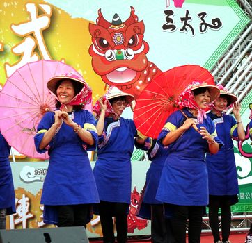 KAOHSIUNG, TAIWAN -- AUGUST 15, 2015: Women dressed in traditional Chinese Hakka costumes perform a dance with bamboo umbrellas at the Third Prince temple carnival.
