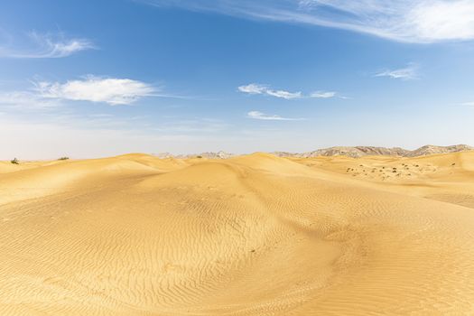 Sand Dunes landscape with Mountains in the background and with blue sky with large copy space