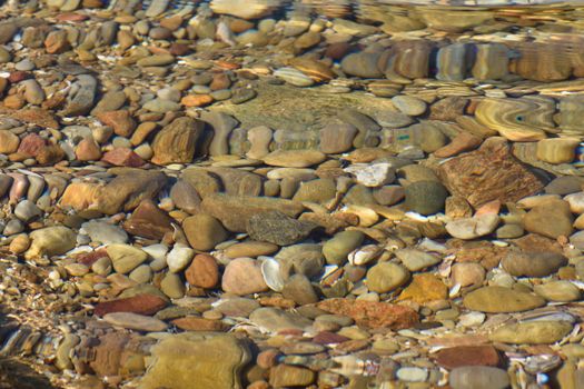 Distorted rocks, pebbles and shells in a natural coastal water pool, Mossel Bay, South Africa