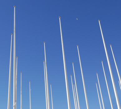 An Array of Flagpoles with no flags against a blue sky