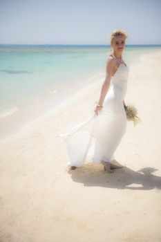 Beautiful woman bride at a tropical beach paradise on wedding day in white gown dress with ocean view