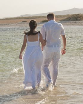 Young newly married couple walking together on a tropical beach