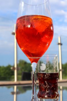 Refreshing orange summer cocktails with cola and ice against a blue sky background. 