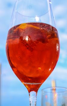 Refreshing orange summer cocktails with cola and ice against a blue sky background. 