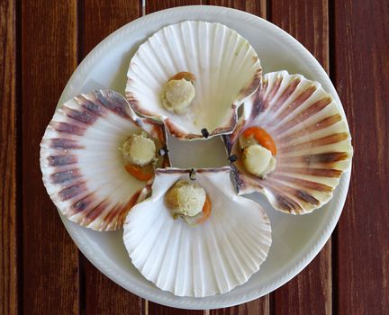 Cooked scallops on a dish on wooden surface of table