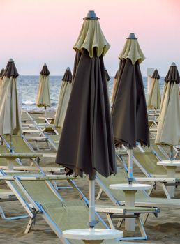 Black and white closed umbrellas on the beach of Rimini in Italy