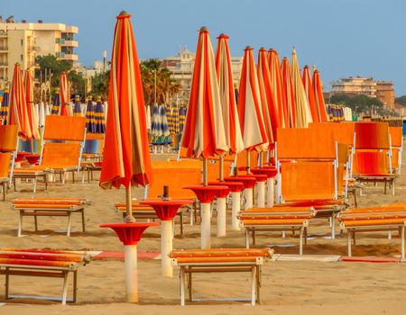 Orange umbrellas and sunbeds on the beach of Rimini in Italy