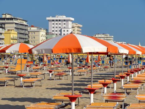 Orange umbrellas and sunbeds on the beach of Rimini in Italy