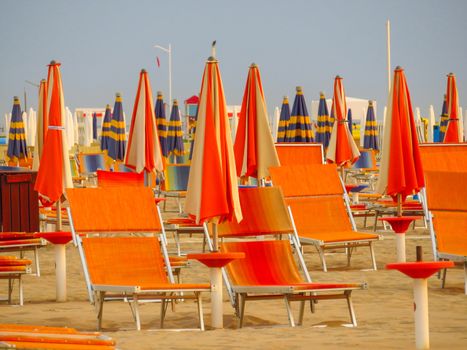 Orange closed umbrellas on the beach of Rimini in Italy