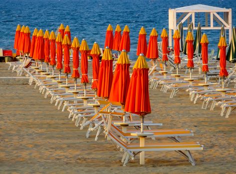 Red umbrellas and sunbeds on the beach of Rimini in Italy