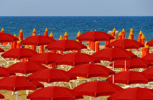 Red umbrellas on the beach of Rimini in Italy