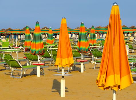 Orange closed umbrellas on the beach of Rimini in Italy