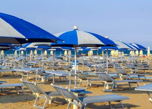 White blue umbrellas and sunbeds on the beach of Rimini in Italy