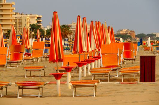White-orange umbrellas and sunbeds on the beach of Rimini in Italy