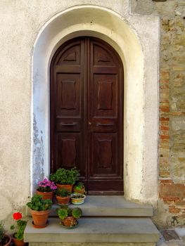 Door of old building with flowers pot in San Leo, Italy