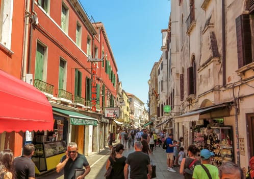 Venice, Italy - June 20, 2017: Architecture of old city in Venice, Italy. Unrecognizable people are walking down the street in the old center.