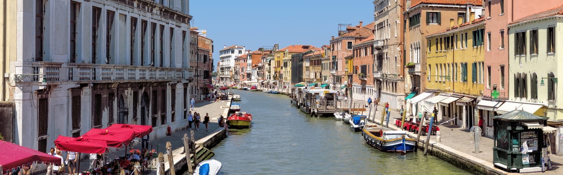 Venice, Italy - June 20, 2017: Beautiful canal in Venice with moorings and old houses under blue sky in the background.