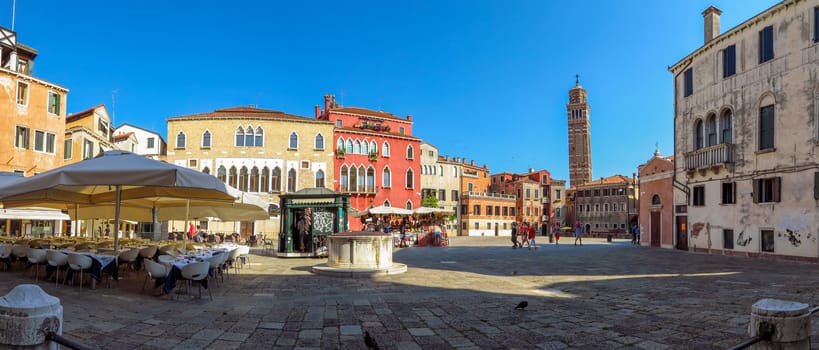 Venice, Italy - June 20, 2017: Panoramic view to architecture of old city in Venice, Italy. Unrecognizable people are walking down the street in the old center.