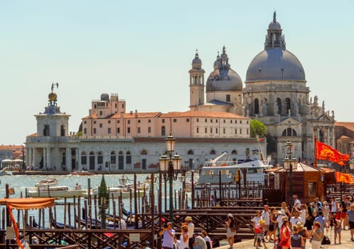 Venice, Italy - June 20, 2017: View to old cathedral of Santa Maria della Salute in Venice, Italy. Unrecognizable people are walking down the street in the old center.