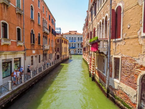 Venice, Italy - June 20, 2017: View from water street to old buildings in Venice, Italy. Unrecognizable people are walking down the street in the old center.