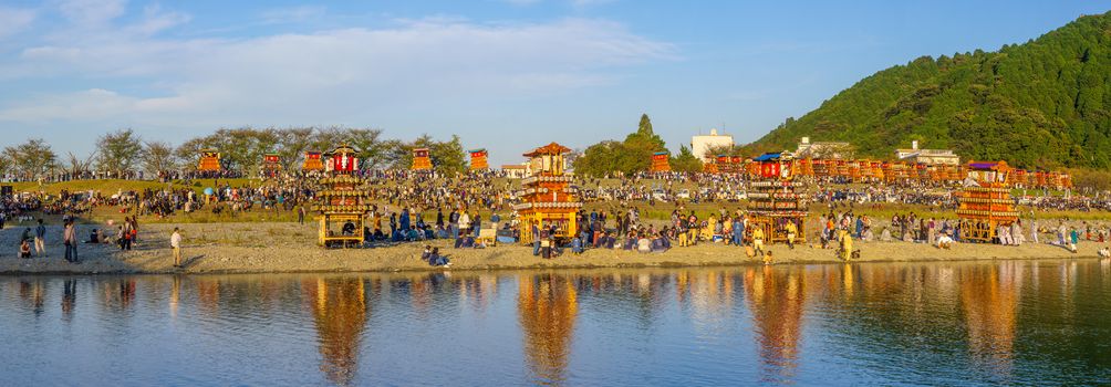 Saijo, Japan - October 16, 2019: Panorama of gathering of participants and Danjiri (portable shrines), on the bank of the Kamogawa River. Saijo Isono Shrine Festival, Ehime, Shikoku Island, Japan
