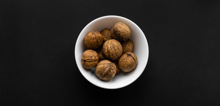 Walnut in a small plate on a black table. Walnuts is a healthy vegetarian protein nutritious food. Natural nuts snacks