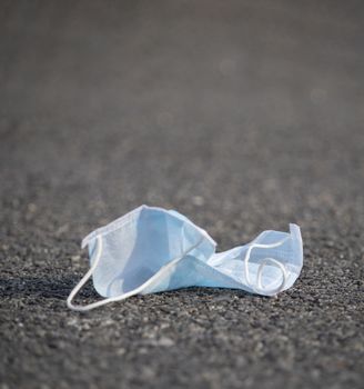 disposed medical face mask on road - concept of unhygienic dispose of masks during covid-19 or coronavirus